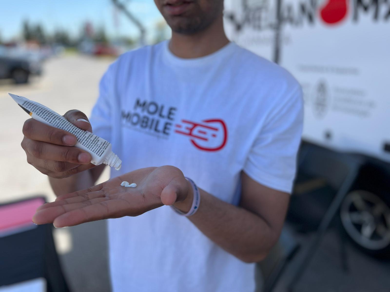 A Mole Mobile team member demonstrating sunscreen during a skin-health education moment.